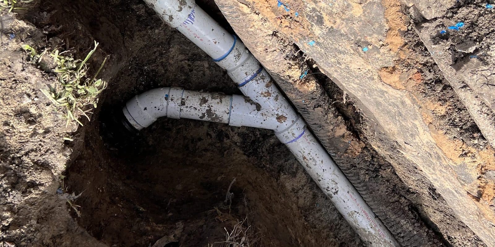 New PVC sewer line laid in an open trench beside the old line it replaces