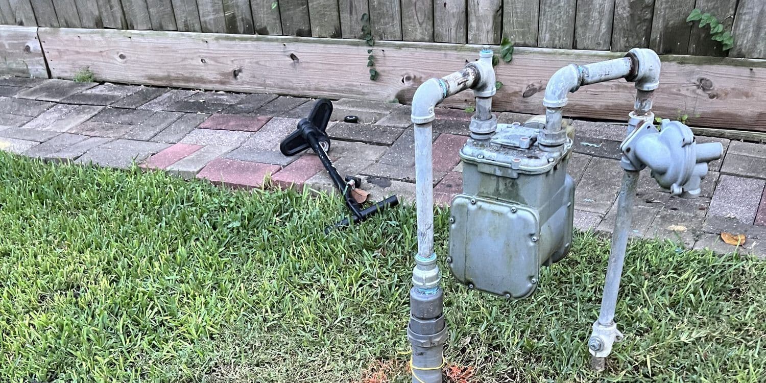 Residential gas meter and riser beside a backyard walkway