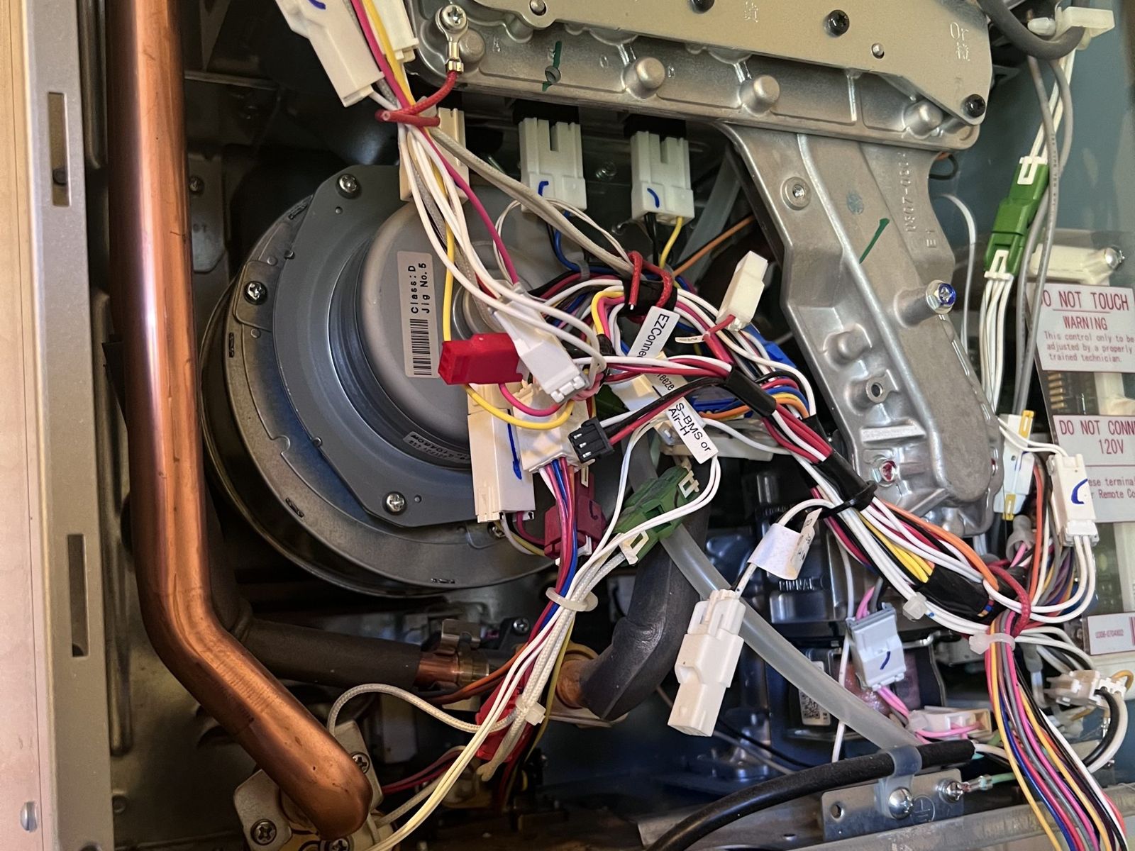 A tankless water heater with the cover off for service. Annual descaling keeps scale out of the heat exchanger inside.