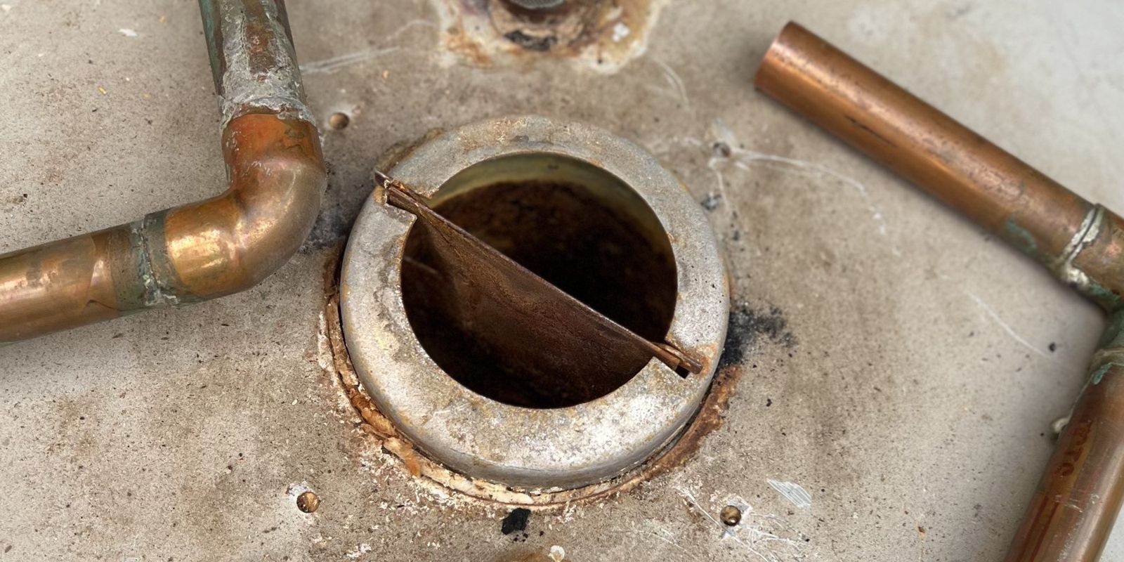 The top of an aging tank water heater: corroded fittings and rust around the flue.